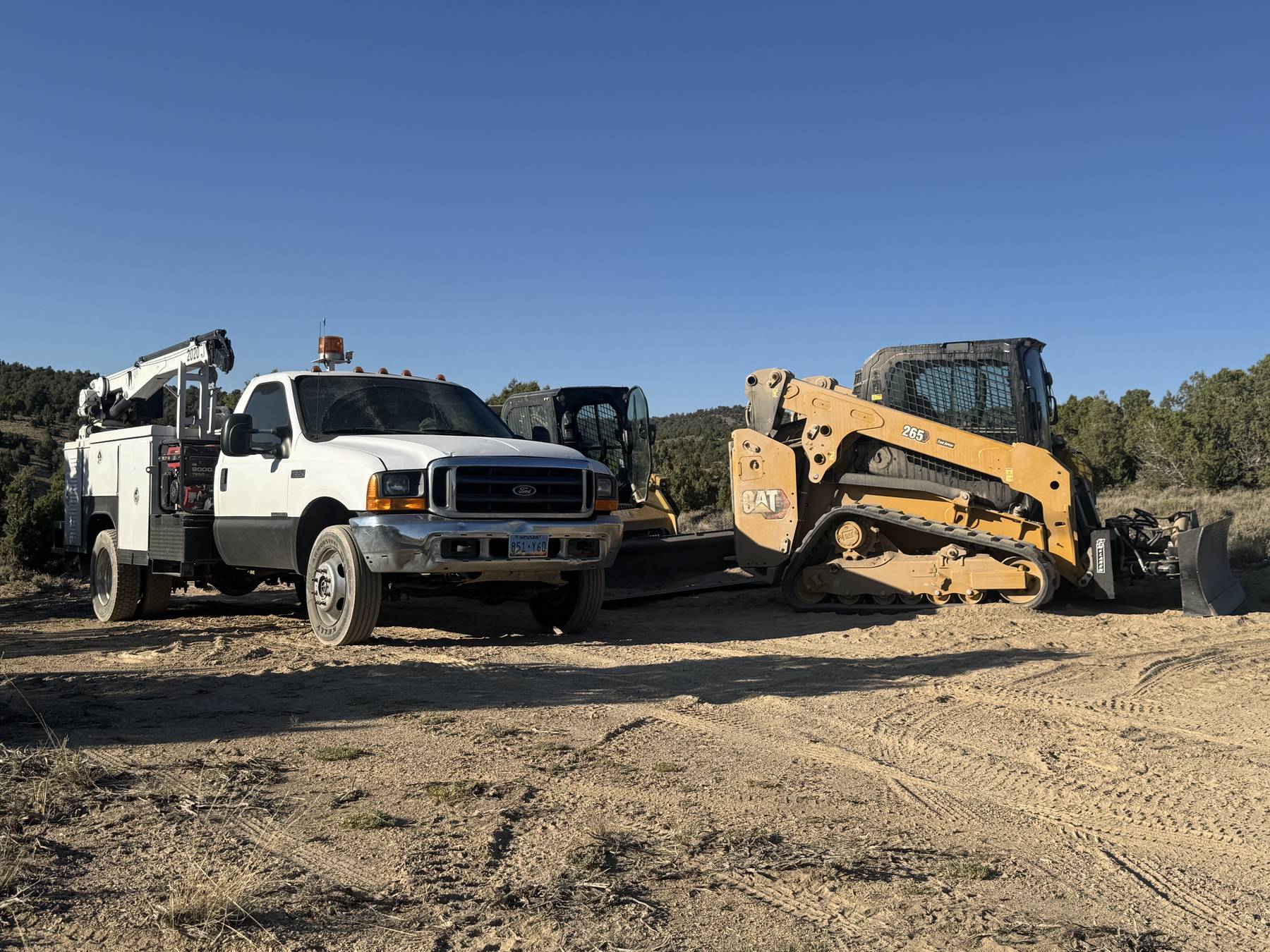 ADSW Repair crane service truck parked beside a Caterpillar 265 compact track loader on a job site